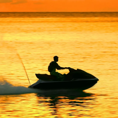 Person on a jet ski during a sunset with orange sky and water.